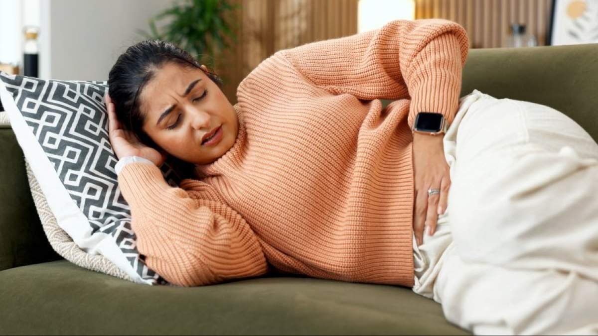 Frau hat Magenprobleme - auf Couch liegend